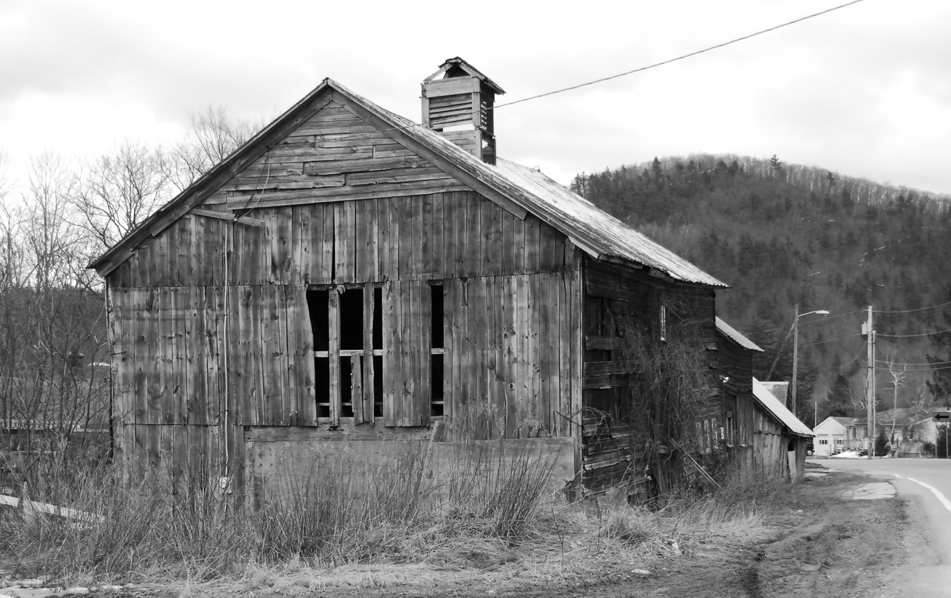 Interior of an abandoned meeting hall, ceiling tiles decaying above a debris-strewn floor.